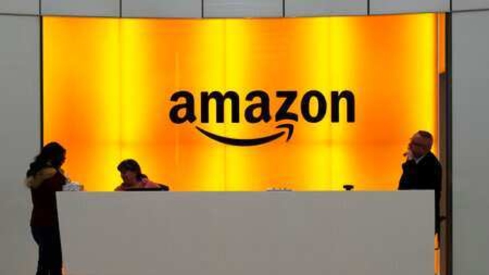 FILE - In this Feb. 14, 2019 file photo, people stand in the lobby for Amazon offices in New York.  Amazon is jumping into the podcast-making business. The online shopping giant said it plans to buy Wondery, a 4-year-old producer of popular true crime podcasts such as “Dr. Death” and “Dirty John.”   (AP Photo/Mark Lennihan, File)