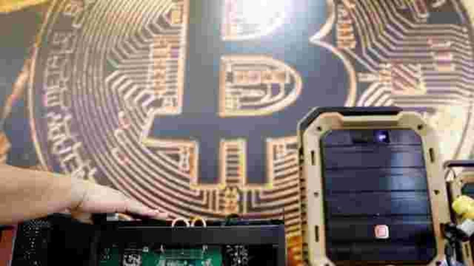A cryptocurrency mining computer is seen in front of bitcoin logo during the annual Computex computer exhibition in Taipei, Taiwan