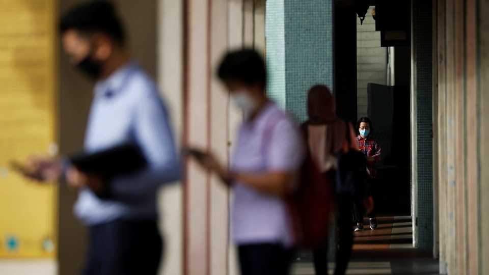 People wearing protective masks wait to cross a street in Singapore. 