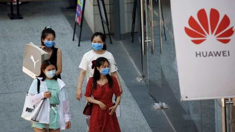 FILE PHOTO: Women wearing face masks following the coronavirus disease (COVID-19) outbreak walk past a Huawei store at a shopping complex in Beijing, China, July 14, 2020. REUTERS/Tingshu Wang