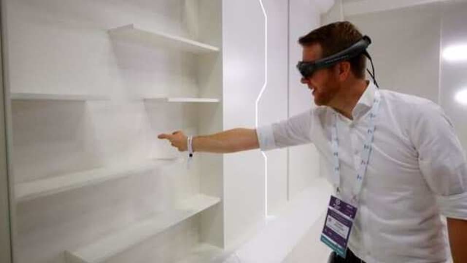 FILE PHOTO: A gamer grabs for a virtual book from an empty shelf as he wears augmented reality goggles during the media day of Europe's leading digital games fair Gamescom, which showcases the latest trends of the computer gaming scene, in Cologne, Germany, August 20, 2019. REUTERS/Wolfgang Rattay/File Photo