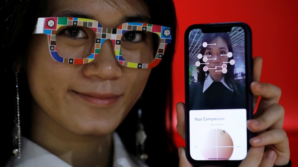 An employee of online fashion retailer Zozo, poses with Zozoglass and its smartphone application, used to measure skin tone for ordering cosmetics online, during a demonstration at the company's office in Tokyo, Japan,