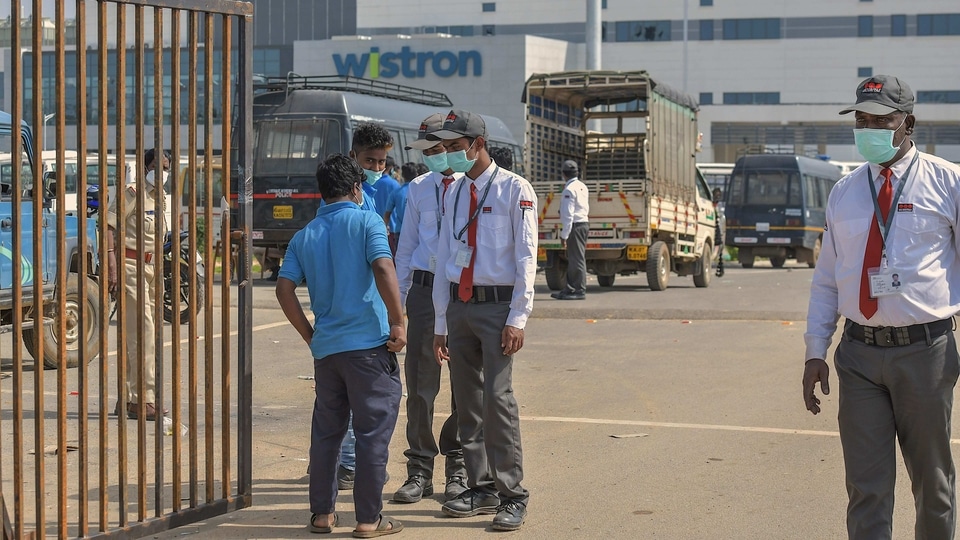 Security personnel stand guard outside Wistron Infocomm Manufacturing India Pvt Ltd, where a section of workers went on a rampage at its facility manufacturing Apple iPhones and other products over non-payment of promised wage, at Narasapura area in Bengaluru.