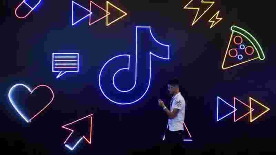 A man holding a phone walks past a sign of Chinese company ByteDance's app TikTok, known locally as Douyin, at the International Artificial Products Expo in Hangzhou, Zhejiang province, China.