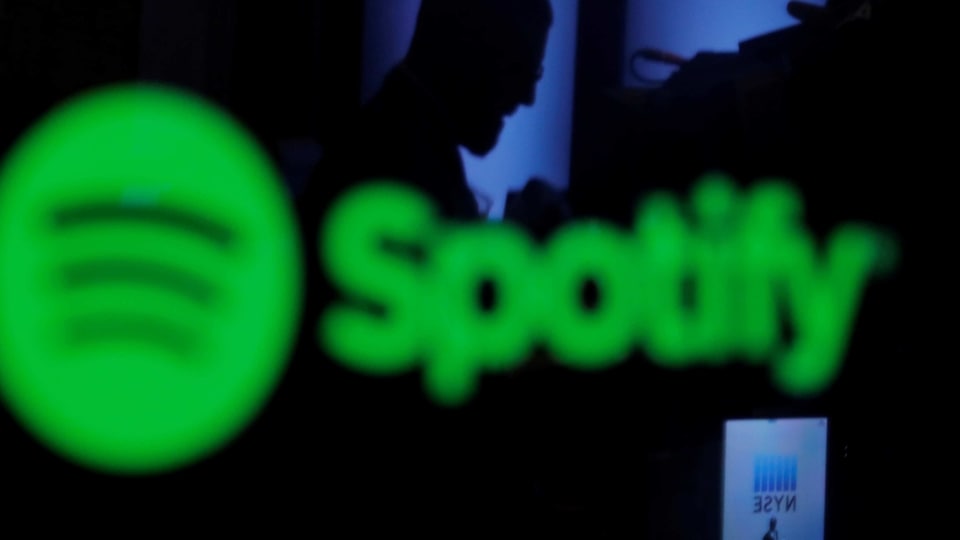 FILE PHOTO: A trader is reflected in a computer screen displaying the Spotify brand before the company begins selling as a direct listing on the floor of the New York Stock Exchange in New York, U.S., April 3, 2018.  REUTERS/Lucas Jackson/File Photo