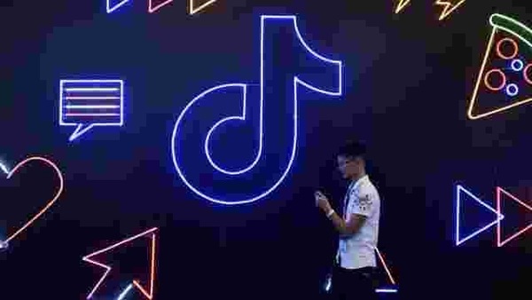 A man holding a phone walks past a TikTok sign, known locally as Douyin, at the International Artificial Products Expo in Hangzhou, Zhejiang province, China.