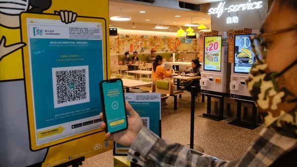 A customer scans a QR code for the LeaveHomeSafe Covid-19 contact-tracing app before entering a Cafe de Coral Holdings Ltd. fast food restaurant in Hong Kong, China, on Thursday, Feb. 18, 2021. Hong Kong extends restaurant hours, double the number of people allowed to sit at one table, and reopen certain venues beginning today, formalizing its plan to roll back restrictions as cases dwindled during the Chinese New Year. Photographer: Roy Liu/Bloomberg