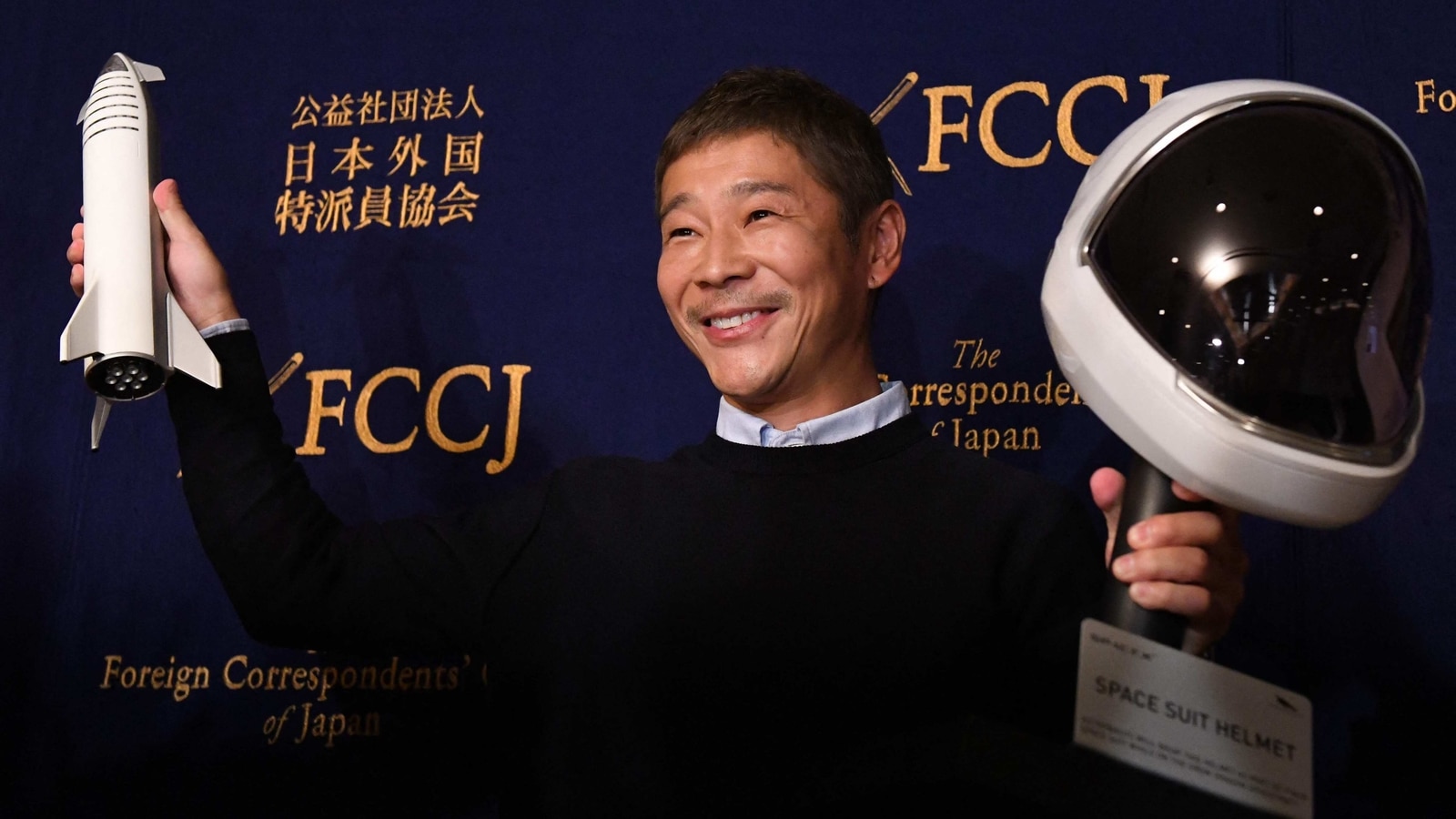 This photo taken on October 9, 2018 shows Japanese billionaire Yusaku Maezawa, the first private passenger who will fly around the Moon aboard the SpaceX BFR launch vehicle, posing with a model rocket and space helmet prior to a press conference in Tokyo. This photo taken on October 9, 2018 shows Japanese billionaire Yusaku Maezawa, the first private passenger who will fly around the Moon aboard the SpaceX BFR launch vehicle, posing with a model rocket and space helmet prior to a press conference in Tokyo.