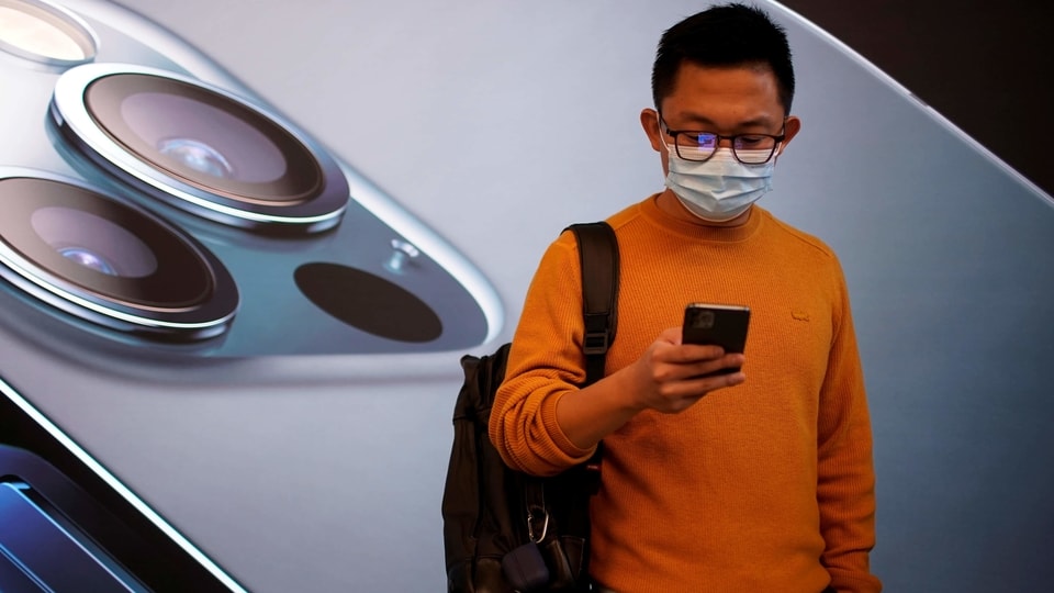 FILE PHOTO: A man wears a face mask while waiting at an Apple Store before Apple's 5G new iPhone 12 go on sale, as the coronavirus disease (COVID-19) outbreak continues in Shanghai China October 23, 2020. REUTERS/Aly Song/File Photo