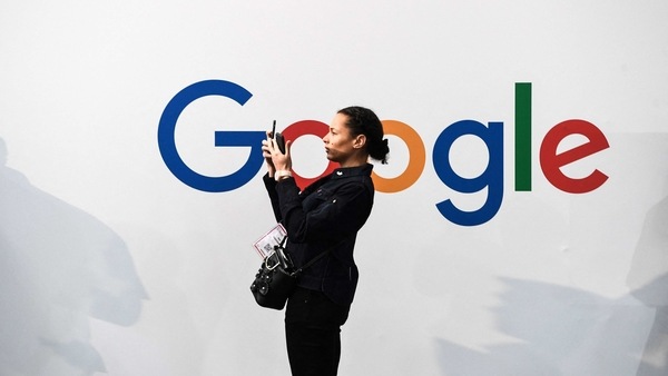 (FILES) In this file photo taken on May 16, 2019, a woman takes a picture with two smartphones in front of the logo of the US multinational technology and Internet-related services company Google as she visits the Vivatech startups and innovation fair, in Paris. - Google said on February 22, 2020 it would lift its ban on political ads on its platform imposed last month following the turmoil surrounding the violent uprising at the US Capitol. (Photo by ALAIN JOCARD / AFP)
