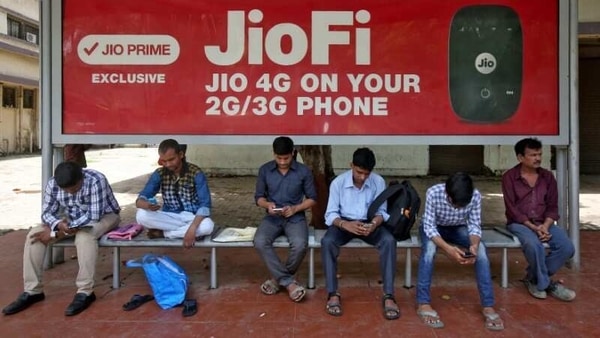 Commuters use their mobile phones as they wait at a bus stop in Mumbai. 
