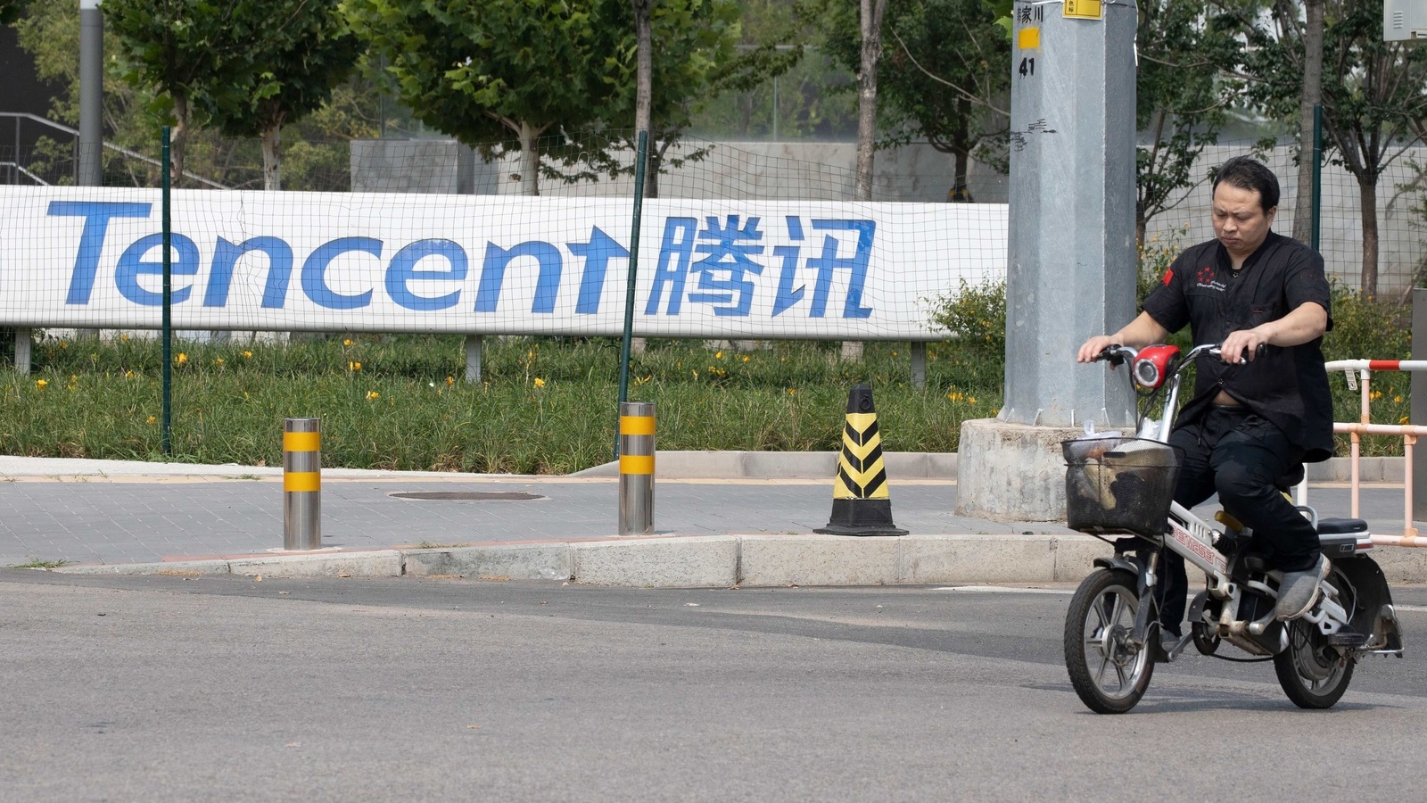 In this file photo, a man rides past the Tencent headquarters in Beijing,