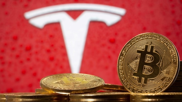 FILE PHOTO: Representations of virtual currency Bitcoin are seen in front of the Tesla logo.