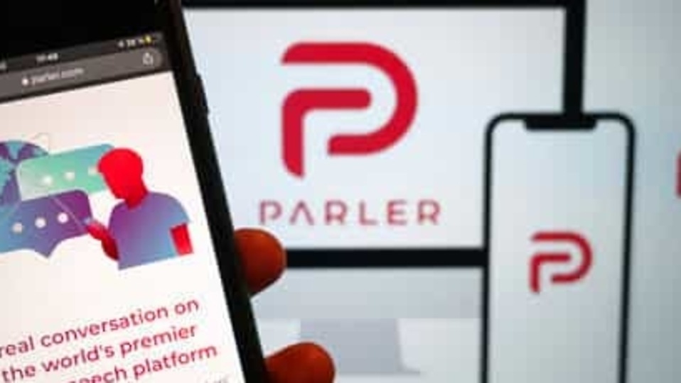 The website of the social media platform Parler is displayed in Berlin, Jan. 10, 2021. The platform's logo is on a screen in the background. The conservative-friendly social network Parler was booted off the internet Monday, Jan. 11, over ties to last week's siege on the U.S. Capitol, but not before hackers made off with an archive of its posts, including any that might have helped organize or document the riot. (Christophe Gateau/dpa via AP)