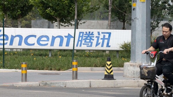 In this file photo, a man rides past the Tencent headquarters in Beijing,