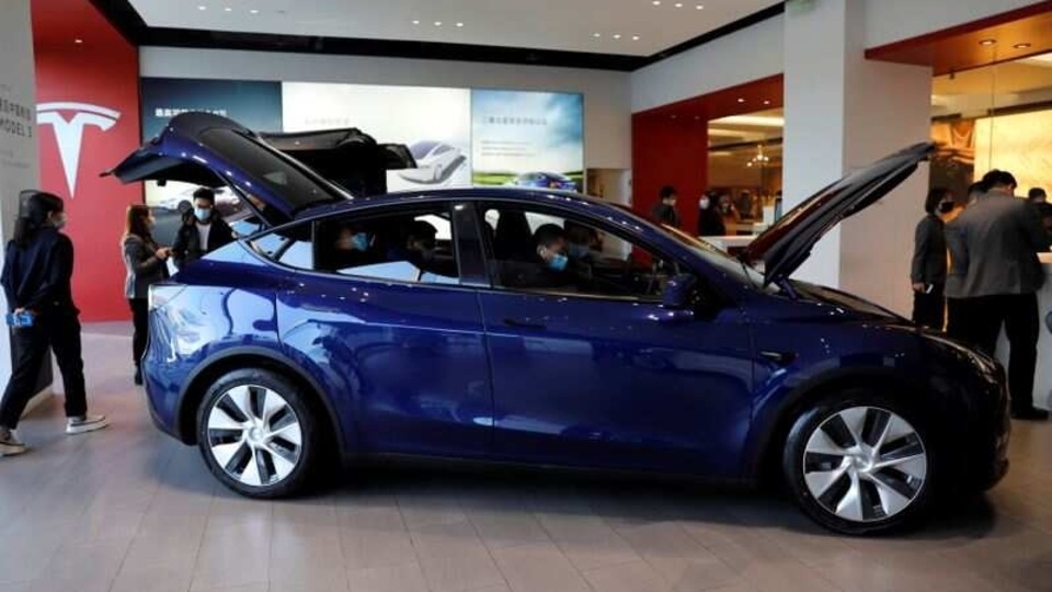 Visitors wearing face masks check a China-made Tesla Model Y sport utility vehicle (SUV) at the electric vehicle maker's showroom in Beijing. 