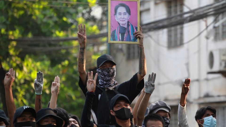 Anti-coup demonstrators raise the three finger of resistance and a portrait of deposed leader Aung San Suu Kyi as prepare to confront police during a protest in Tarmwe township, Yangon, Myanmar, Thursday, April 1, 2021. (AP Photo)