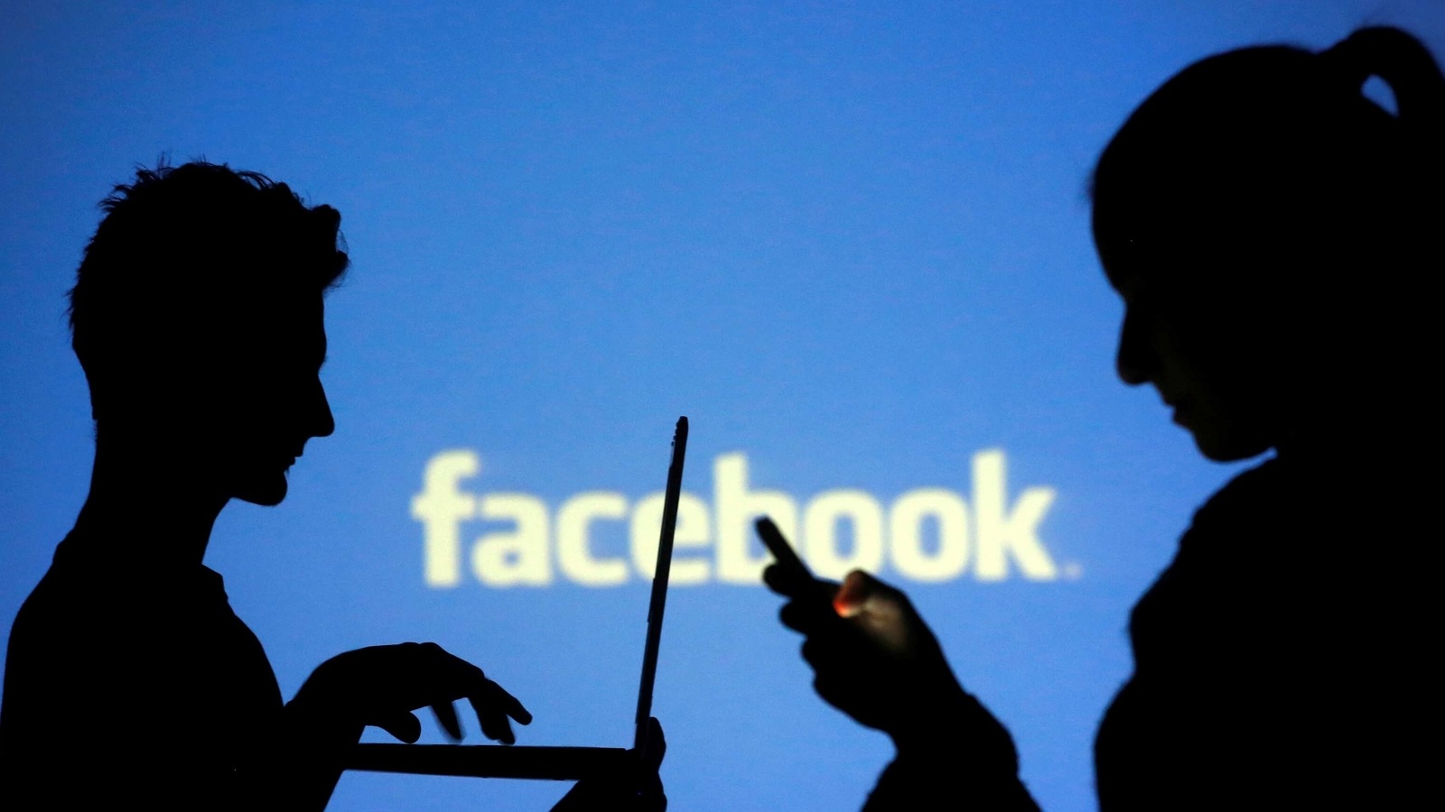 FILE PHOTO: People are silhouetted as they pose with laptops in front of a screen projected with a Facebook logo, in this picture illustration taken in Zenica October 29, 2014. REUTERS/Dado Ruvic/File Photo