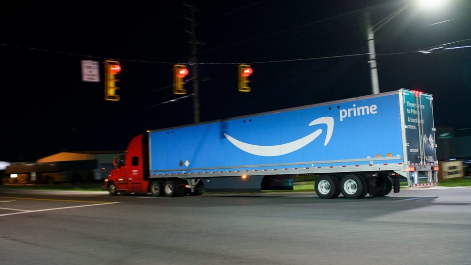 A truck carries a trailer with the Amazon Prime logo past the Amazon fulfillment center in Bessemer, Alabama.