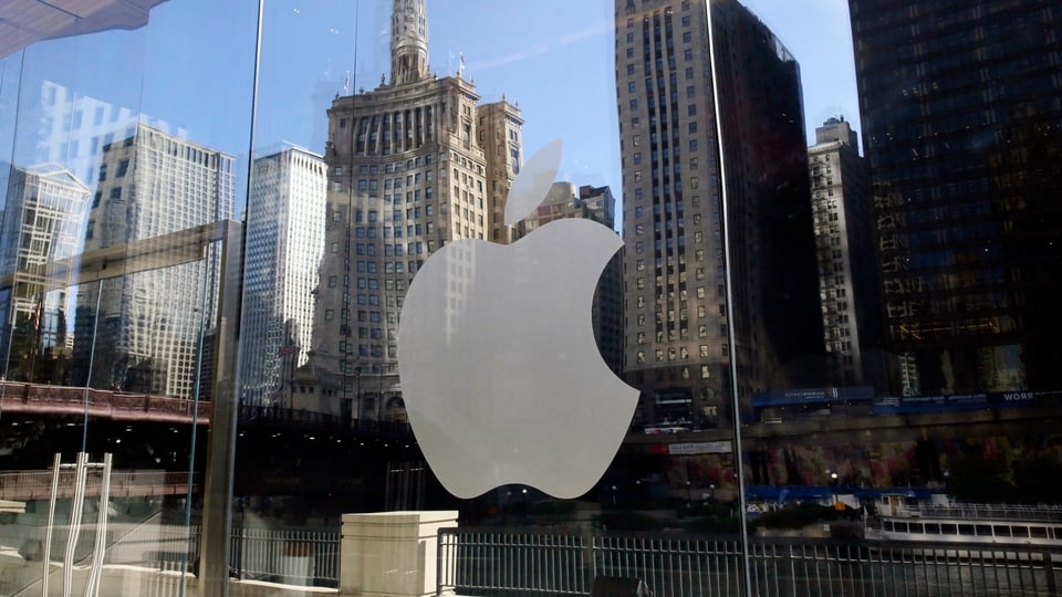 FILE - In this Thursday, Oct. 19, 2017, file photo, buildings are reflected behind the logo at an Apple Store in downtown Chicago.