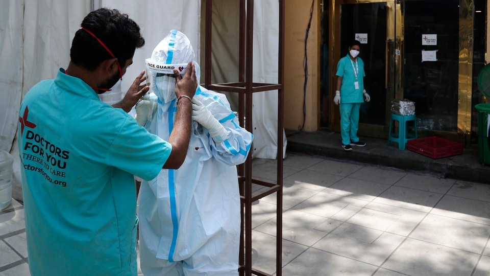 FILE PHOTO - In this April 19, 2021, file photo, a health worker adjusts the face shield of another as she prepares to go inside a quarantine center for COVID-19 patients in New Delhi, India.