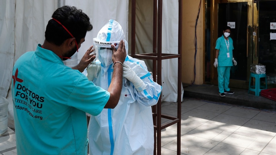 FILE PHOTO - In this April 19, 2021, file photo, a health worker adjusts the face shield of another as she prepares to go inside a quarantine center for COVID-19 patients in New Delhi, India.