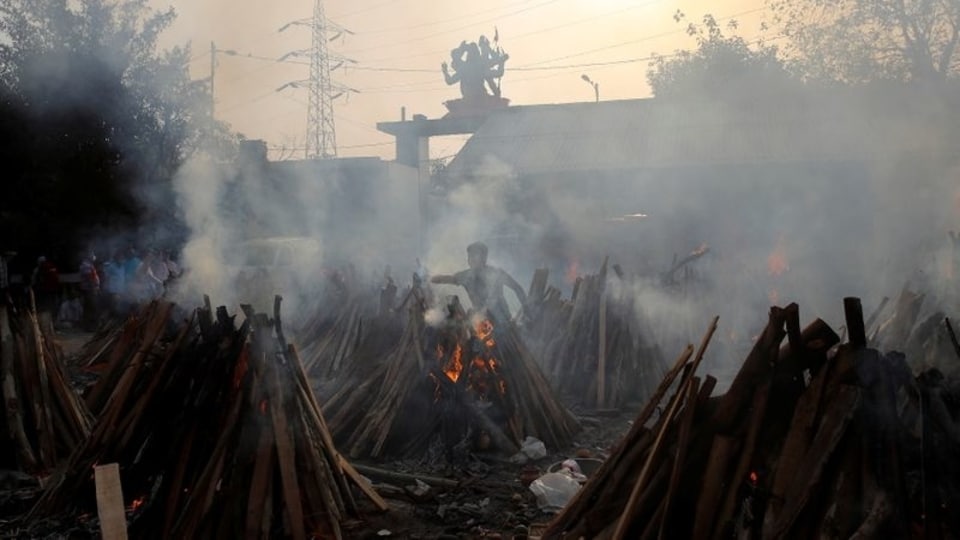A man performs last rites next to the funeral pyres of those who died from the coronavirus disease (COVID-19), during a mass cremation at a crematorium in New Delhi, India May 1, 2021. 