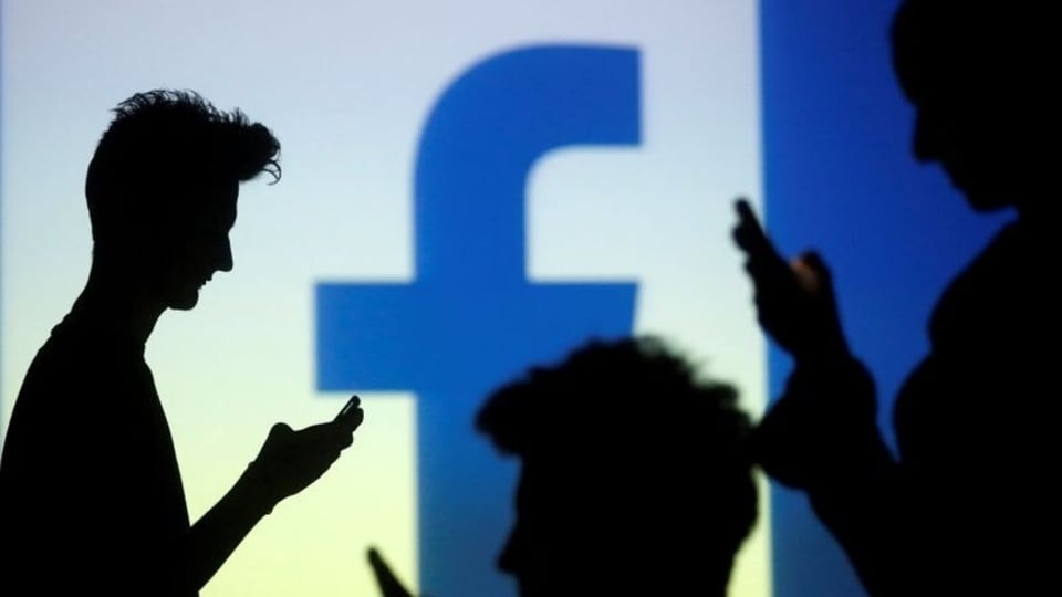 FILE PHOTO: People are silhouetted as they pose with mobile devices in front of a screen projected with a Facebook logo, in this picture illustration taken in Zenica October 29, 2014.