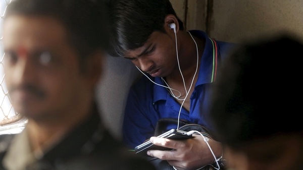FILE PHOTO: A man watches a video on his mobile phone as he commutes by a suburban train in Mumbai, India. Picture taken March 31, 2016.