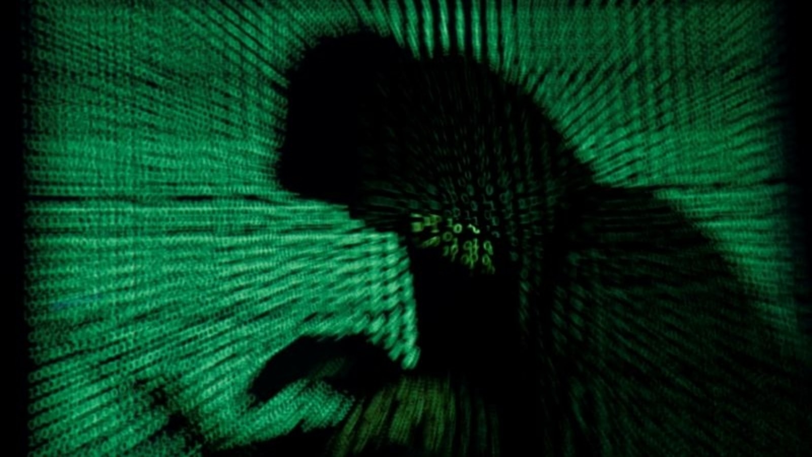 FILE PHOTO: A hooded man holds a laptop computer as cyber code is projected on him in this illustration picture taken on May 13, 2017. Top U.S. fuel pipeline operator Colonial Pipeline has shut its entire network after a cyber attack, the company said on Friday.&nbsp;