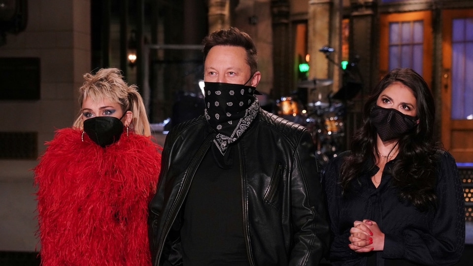 This image released by NBC shows musical guest Miley Cyrus, from left, host Elon Musk, and Cecily Strong during promos in Studio 8H on Thursday, May 6, 2021. (Rosalind O'Connor/NBC via AP)