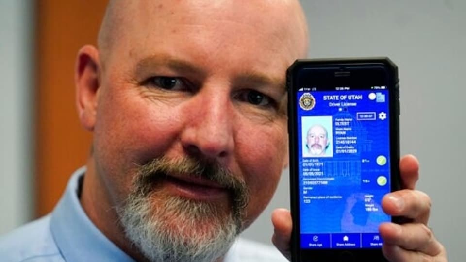 Ryan Williams, with the Utah Drivers License Division, displayes his cell phone with the pilot version of the state's mobile ID on Wednesday, May 5, 2021, in West Valley City, Utah. The card that millions of people use to prove their identity to everyone from police officers to liquor store owners may soon be a thing of the past as a growing number of states develop digital driver's licenses. In Utah, over 100 people have a pilot version of the state's mobile ID, and that number is expected to grow to 10,000 by year's end. Widespread production is expected to begin at the start of 2022. (AP Photo/Rick Bowmer)