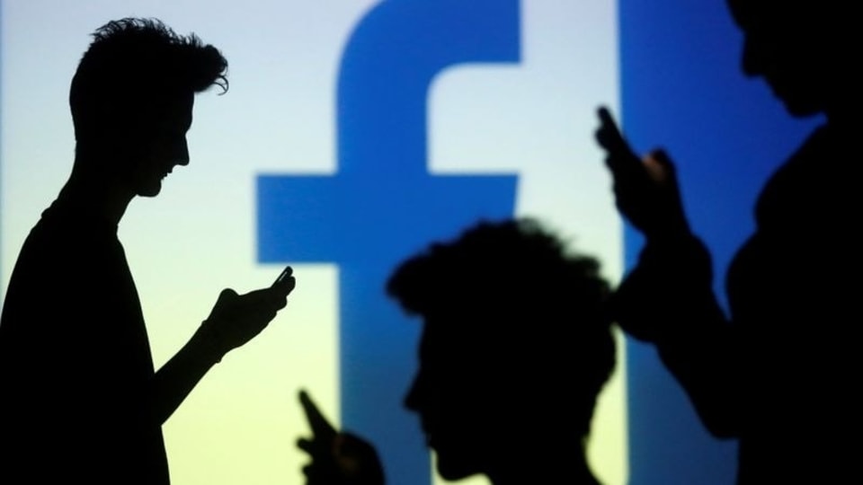 FILE PHOTO: People are silhouetted as they pose with mobile devices in front of a screen projected with a Facebook logo, in this picture illustration taken in Zenica October 29, 2014.