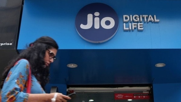 FILE PHOTO: A woman checks her mobile phone as she walks past a mobile store of Reliance Industries' Jio telecoms unit, in Mumbai, India, July 11, 2017. 