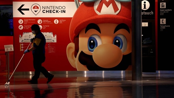 A cleaner mops the floor in front of a Nintendo's Super Mario game character decoration at Narita Airport in China prefecture on June 1, 2021.