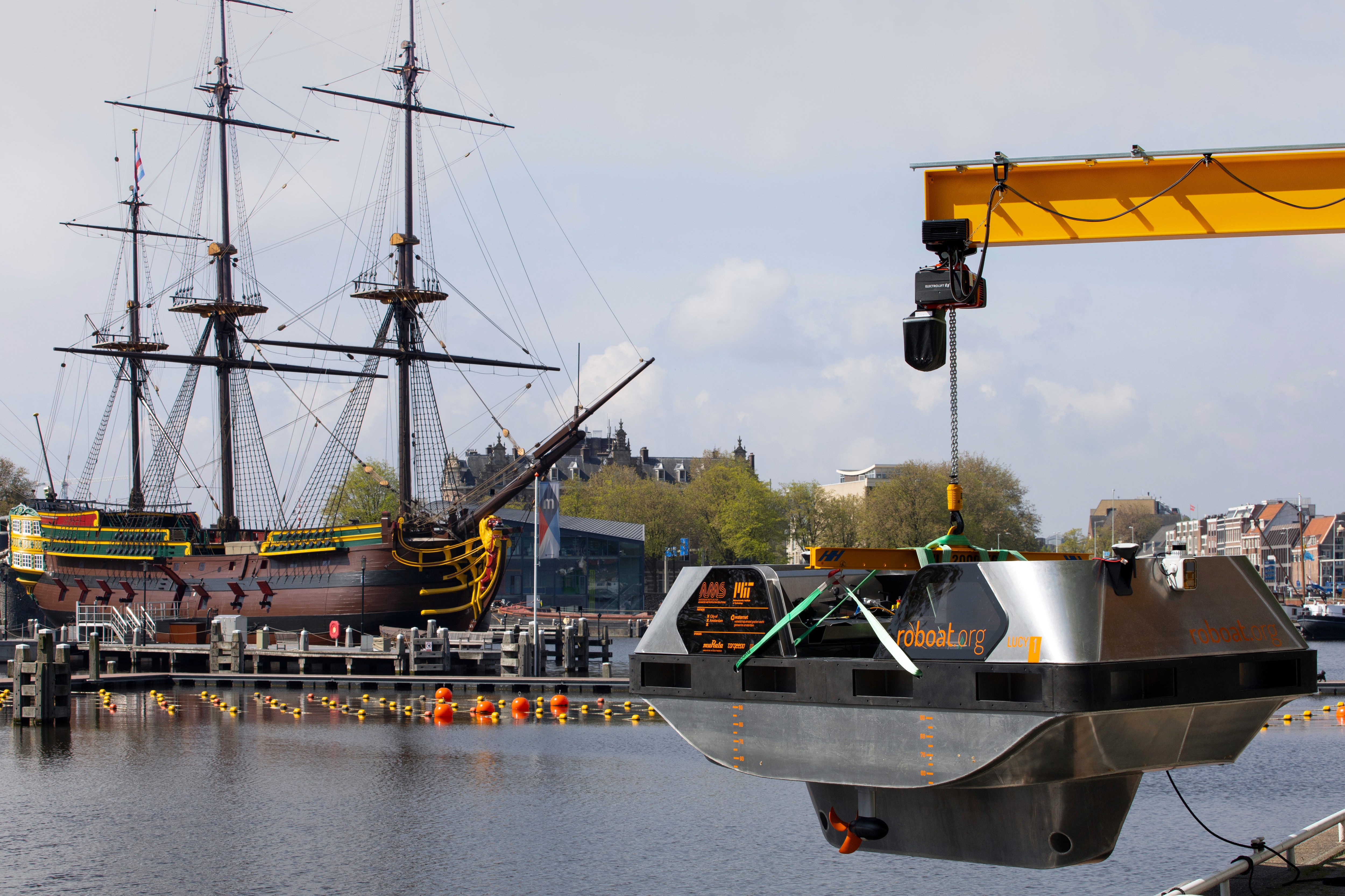 An electric boat is lowered outside a workshop with a full-size replica of the 18th century three-mast trading ship Amsterdam at the National Maritime Museum in the background, in Amsterdam, Thursday, May 20, 2021. Already steeped in maritime history, the city's more than 100 kilometers (60 miles) of waterways are to start hosting prototypes of futuristic boats — small, fully-autonomous electric vessels — to carry out tasks including transporting passengers and picking up garbage. (AP Photo/Peter Dejong) An electric boat is lowered outside a workshop with a full-size replica of the 18th century three-mast trading ship Amsterdam at the National Maritime Museum in the background, in Amsterdam, Thursday, May 20, 2021. Already steeped in maritime history, the city's more than 100 kilometers (60 miles) of waterways are to start hosting prototypes of futuristic boats — small, fully-autonomous electric vessels — to carry out tasks including transporting passengers and picking up garbage. (AP Photo/Peter Dejong)