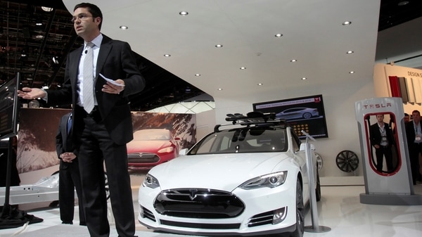 Jerome Guillen speaks in front of a Tesla S electric car during the press preview day of the North American International Auto Show in Detroit, Michigan January 14, 2014.