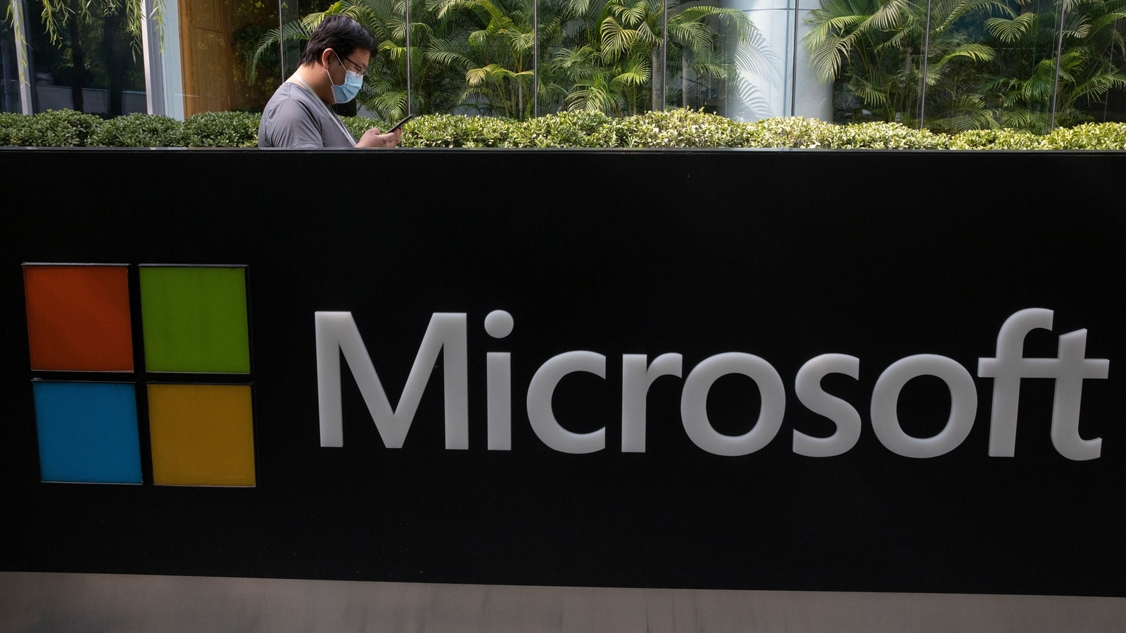 FILE PHOTO - A man wearing a mask looks at this phone outside the Microsoft office in Beijing, China on Friday, Aug. 7, 2020 