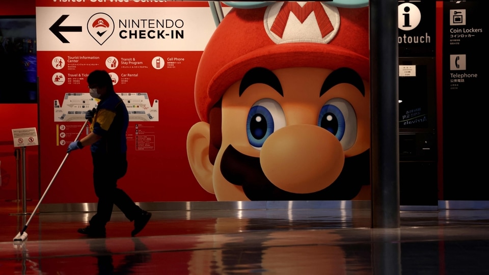 FILE PHOTO: A cleaner mops the floor in front of a Nintendo's Super Mario game character decoration at Narita Airport in China prefecture on June 1, 2021.