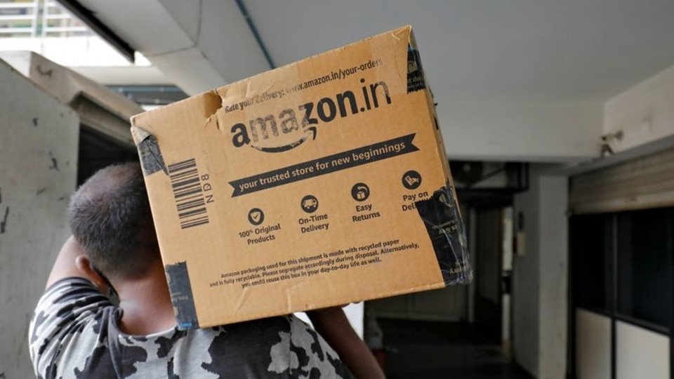 FILE PHOTO: A delivery worker carries an Amazon package to deliver it to a customer at a residential apartment in Ahmedabad, India, March 17, 2021.REUTERS/Amit Dave/File Photo