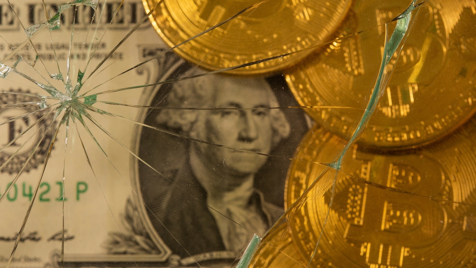 Representations of virtual currency bitcoin on top of a U.S. dollar banknote are pictured through broken glass in this illustration taken June 25, 2021. REUTERS/Dado Ruvic/Illustration