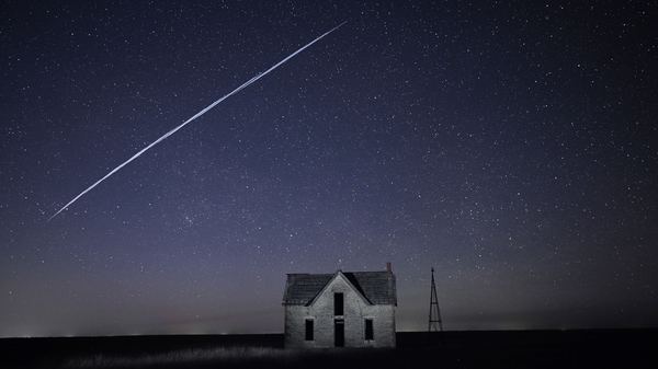 In this photo made with a long exposure, a string of SpaceX StarLink satellites passes over an old stone house near Florence, Kan., on Thursday, May 6, 2021. 