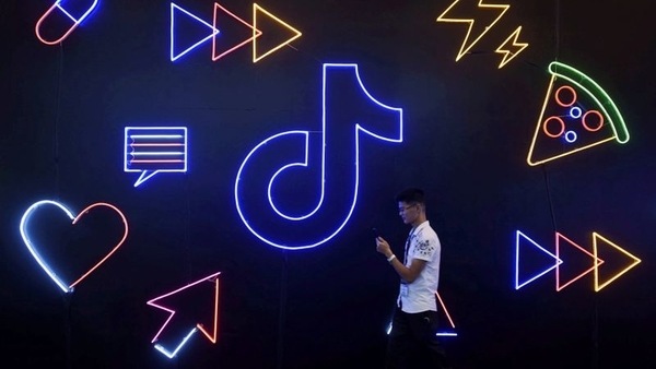 FILE PHOTO: A man holding a phone walks past a sign of Chinese company ByteDance's app TikTok, known locally as Douyin, at the International Artificial Products Expo in Hangzhou, Zhejiang province, China October 18, 2019.