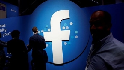 FILE PHOTO: Attendees walk past a Facebook logo during Facebook Inc's F8 developers conference in San Jose, California, U.S., April 30, 2019.