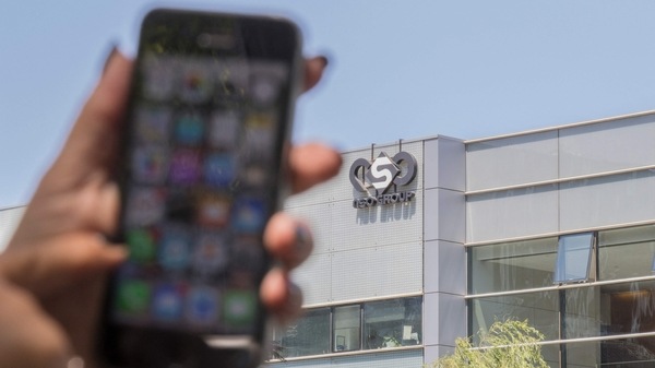 A woman uses her iPhone in front of the building housing the Israeli NSO group