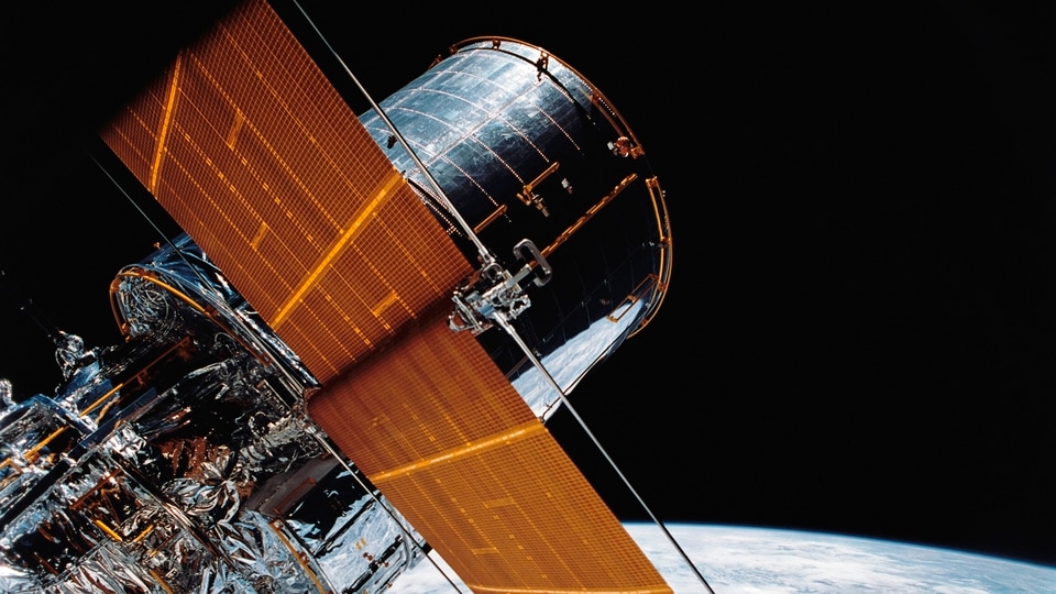 The Hubble Space Telescope can be seen as it is suspended in space by Discovery's Remote Manipulator System (RMS) following the deployment of part of its solar panels and antennae. 