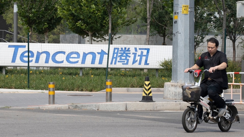 In this file photo, a man rides past the Tencent headquarters in Beijing,