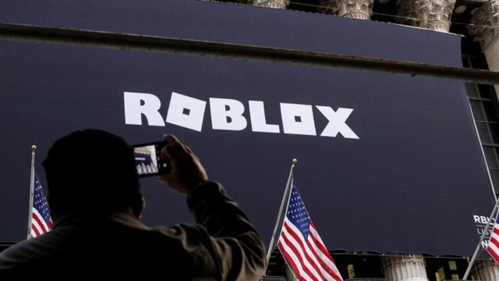 A man photographs a Roblox banner displayed, to celebrate the company's IPO, on the front facade of the New York Stock Exchange (NYSE) in New York, U.S., March 10, 2021. REUTERS/Brendan McDermid/Files