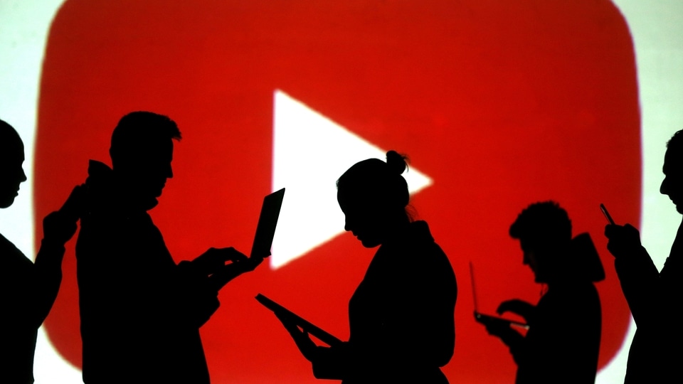 FILE PHOTO: Silhouettes of laptop and mobile device users are seen next to a screen projection of the YouTube logo in this picture illustration taken March 28, 2018.  REUTERS/Dado Ruvic/Illustration/File Photo