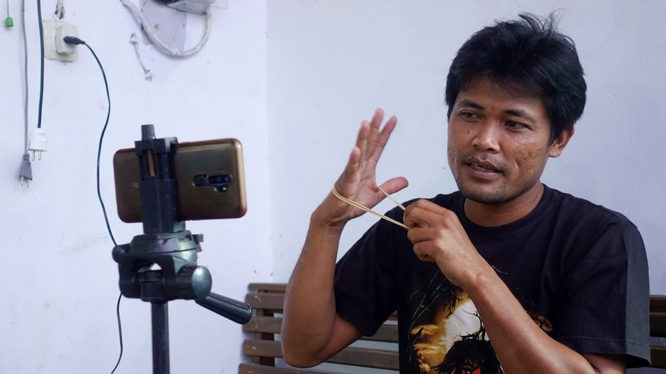 This picture taken on June 20, 2021 shows Indonesian YouTuber Siswanto recording one of his videos at his home in a farming community in Banyuwangi. - Siswanto was a down-on-his-luck mechanic until his improbable pivot to internet videos turned his neighbours into stars and vaulted his poor farming community into the limelight as Indonesia's 